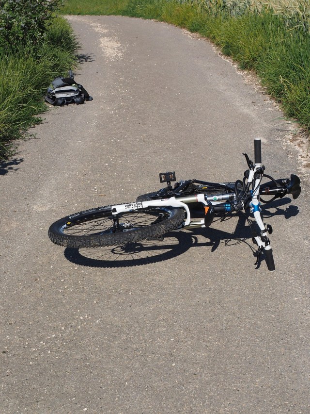 an image of a bicycle laying on its side on a sidewalk