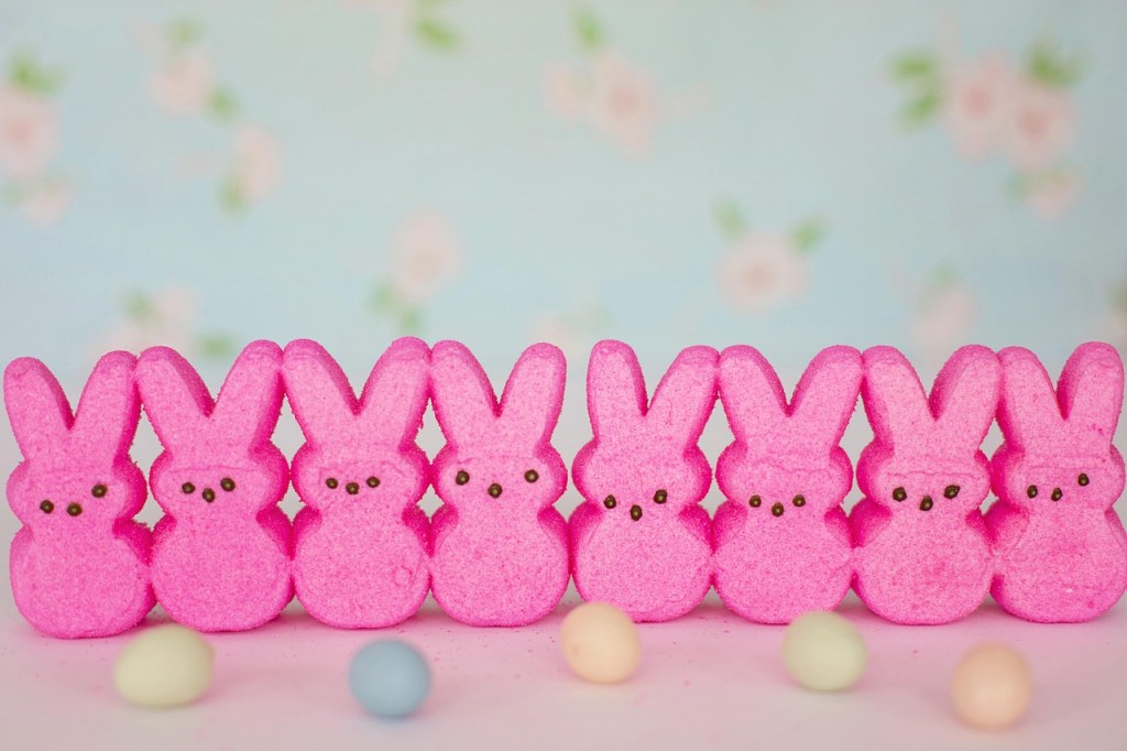 A photo of pink peeps candy and some pastel little chocolate eggs