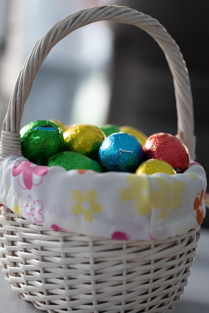 Photo of a lined easter basket filled with foil wrapped easter candy eggs