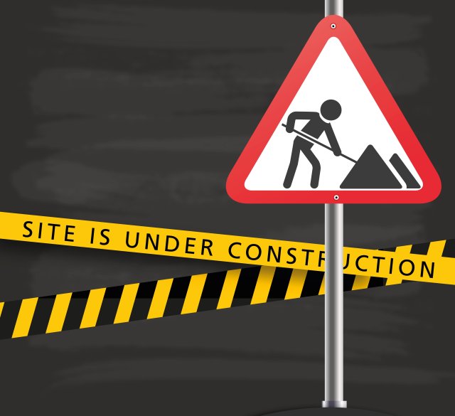 Image of a sign and yellow caution guards that are for "Under Construction"