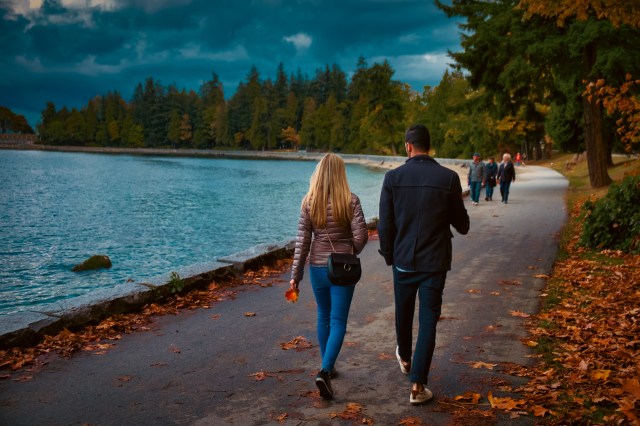 People going for a walk on a beautiful day along a shoreline in the autumn with leaves nearby